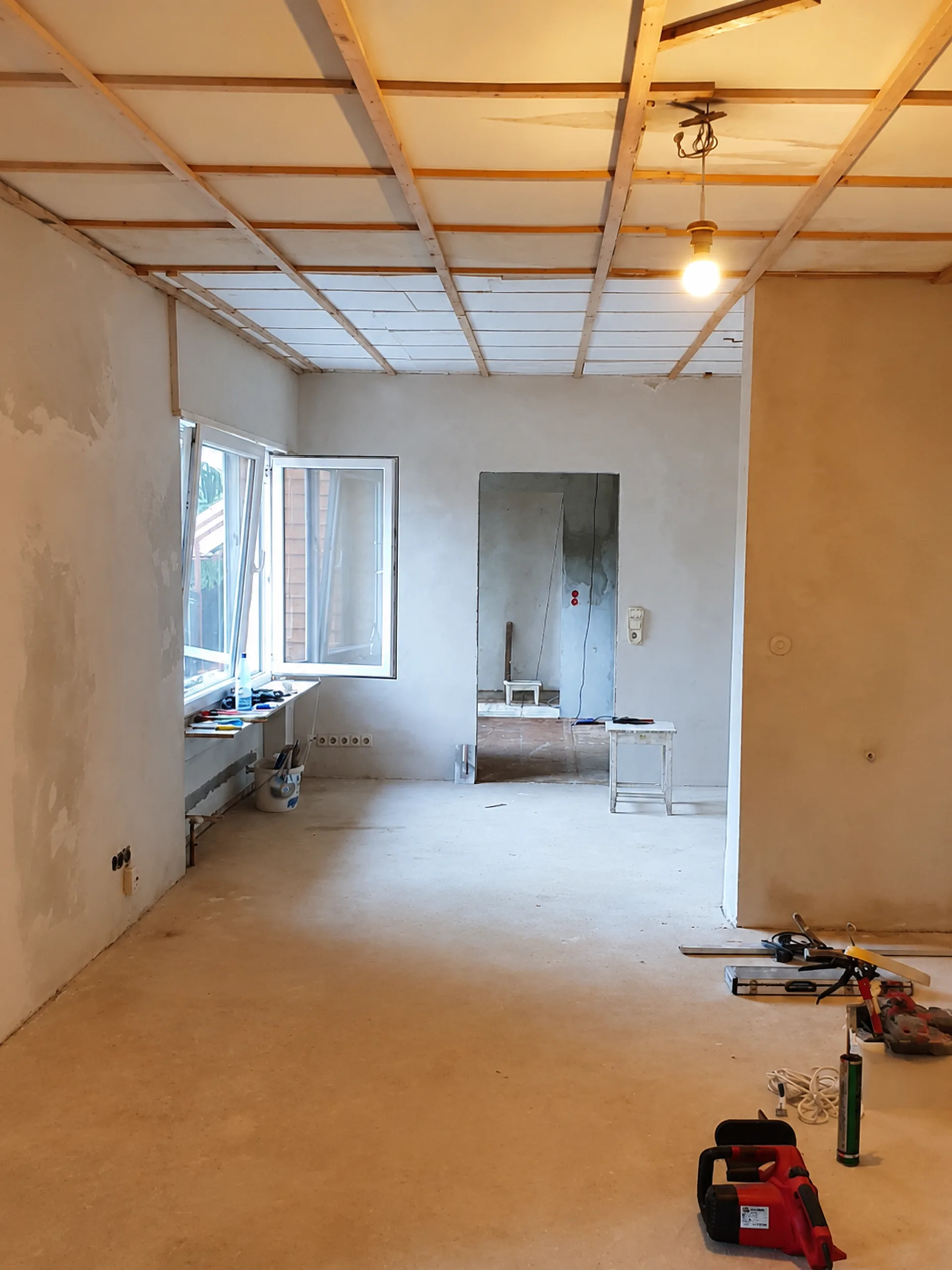 Wohnraum im Rohbau mit sichtbaren Deckenlatten vor dem Ausbau